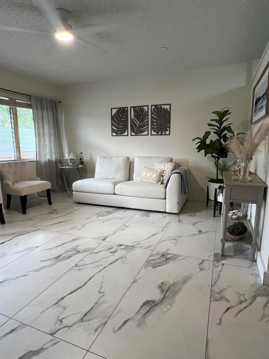 A living room features a white sofa, marble-look tile flooring, and a small accent chair — 900 SW 10th Terrace # S20, Hallandale Beach FL 33009, HALLANDALE BEACH, FL