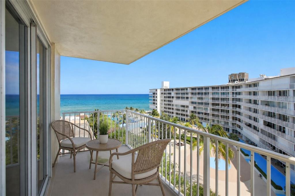 A balcony with two wicker chairs and a small table overlooks the ocean and pool — 3540 S OCEAN BOULEVARD UNIT 808W, PALM BEACH, FL