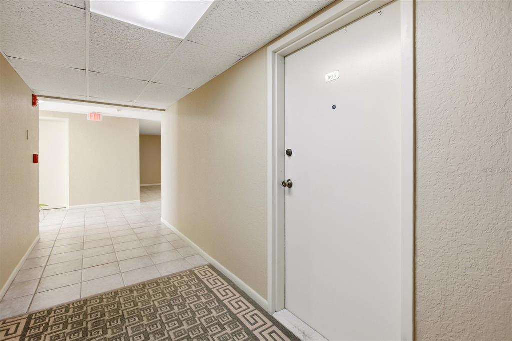 A hallway with a patterned carpet, tiled floor, and a white door labeled 808 — 3540 S OCEAN BOULEVARD UNIT 808W, PALM BEACH, FL