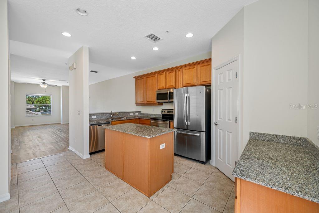 A kitchen features light wood cabinets, granite countertops, stainless steel appliances, and tile flooring — 7125 102ND LANE, SEMINOLE, FL