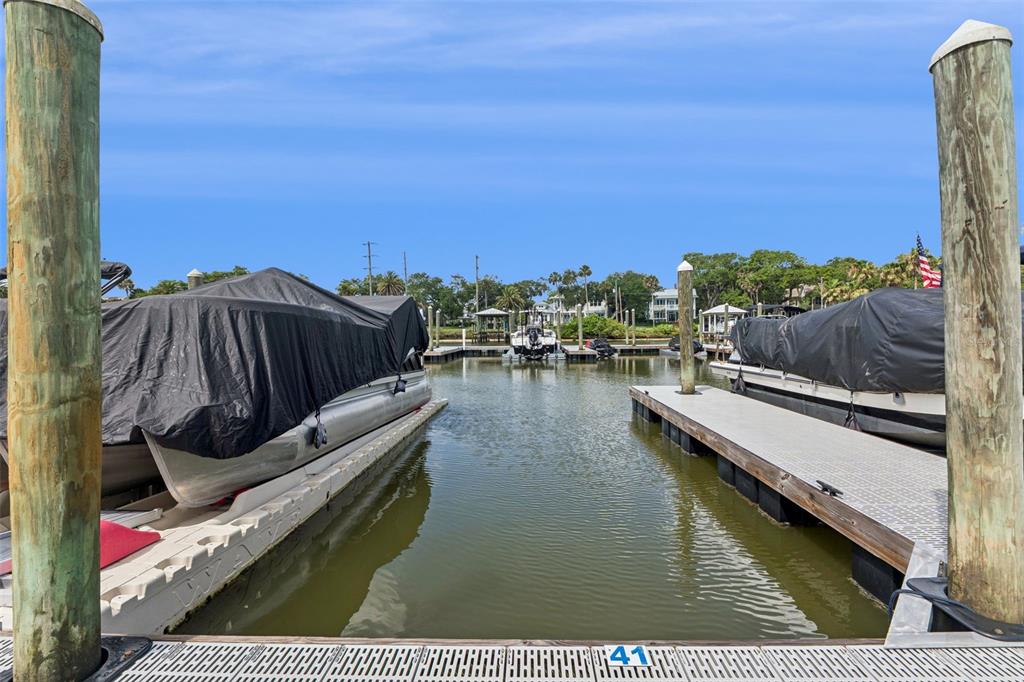 Two boats covered in black tarps are docked in a slip at a marina — 3 RIVERWALK DRIVE UNIT 404, NEW SMYRNA BEACH, FL