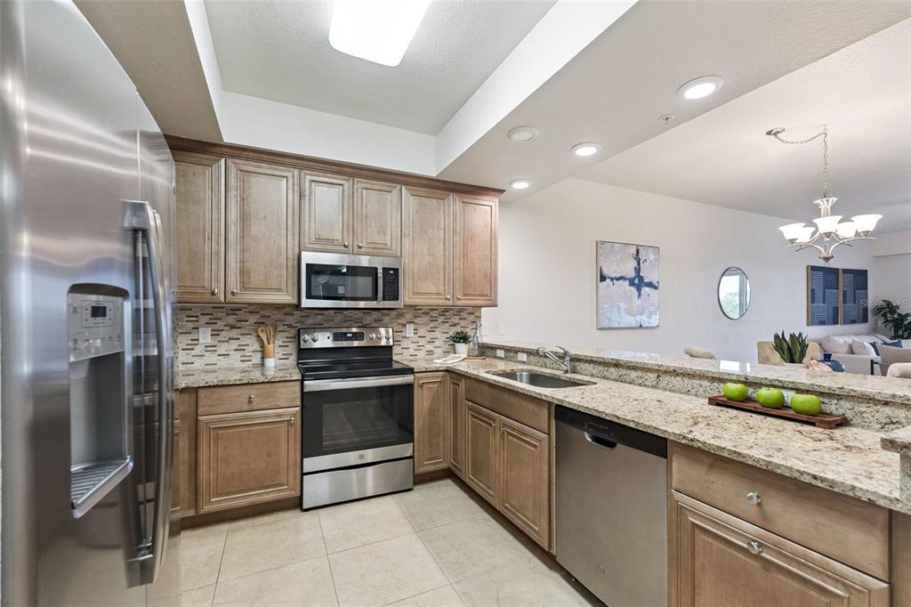 A kitchen with wood cabinets, granite countertops, stainless steel appliances, and tile flooring — 3 RIVERWALK DRIVE UNIT 404, NEW SMYRNA BEACH, FL