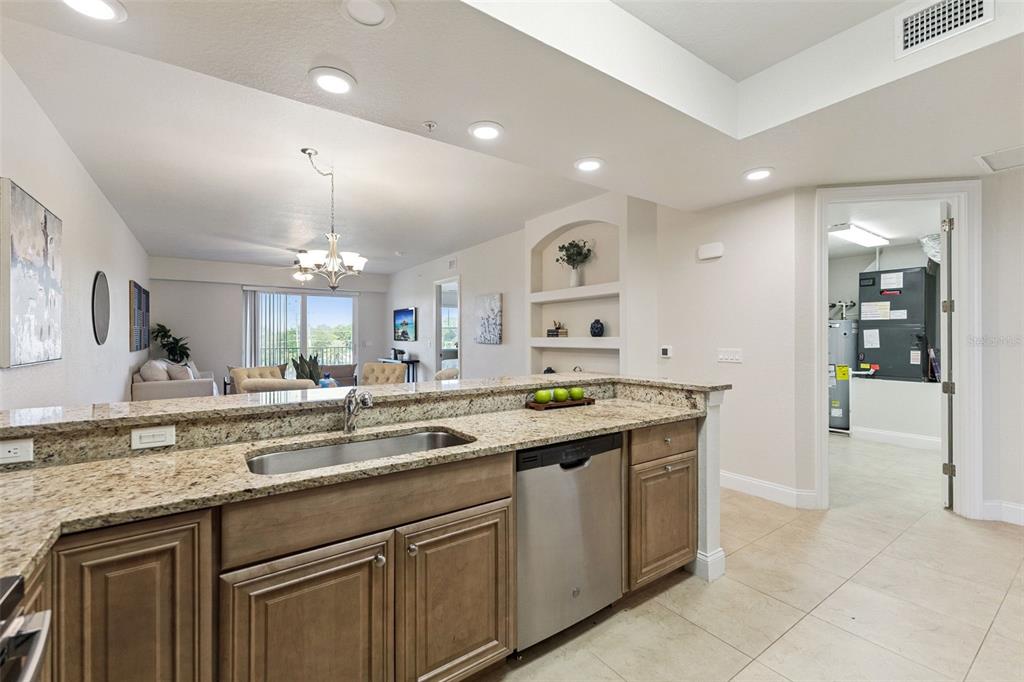 A kitchen with granite countertops and stainless steel appliances overlooks a living area — 3 RIVERWALK DRIVE UNIT 404, NEW SMYRNA BEACH, FL