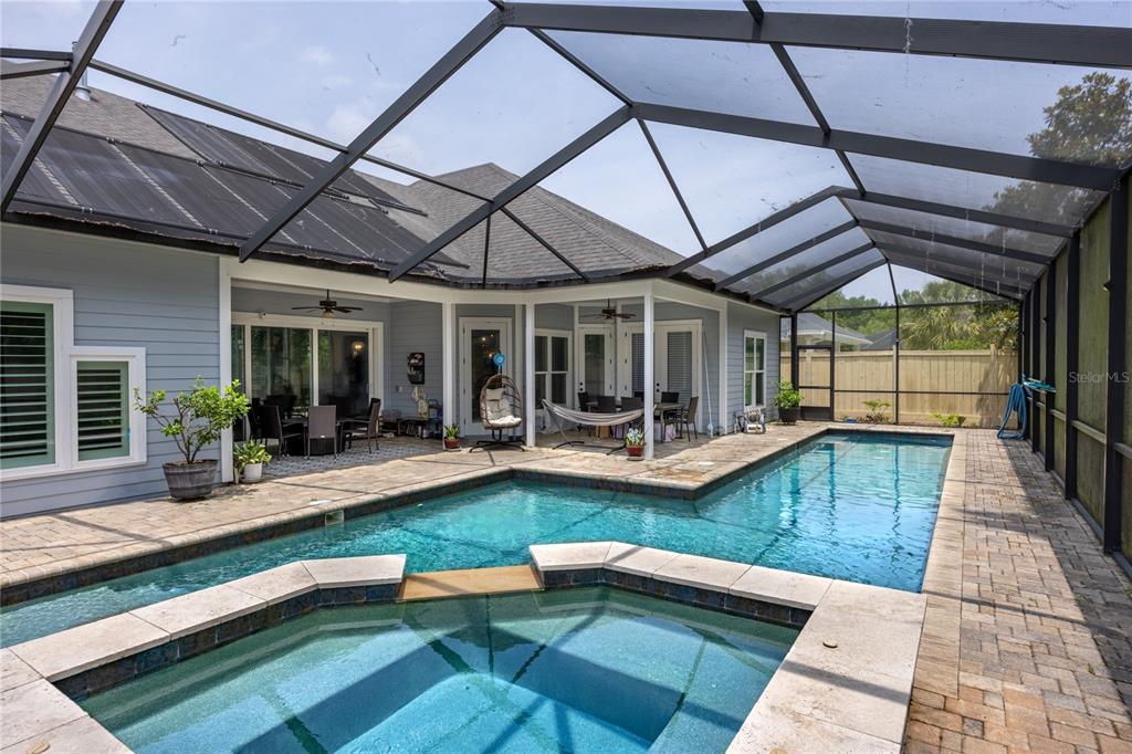 A screened-in patio features a swimming pool, a hot tub, and outdoor dining furniture — 4003 NW 63RD WAY, GAINESVILLE, FL