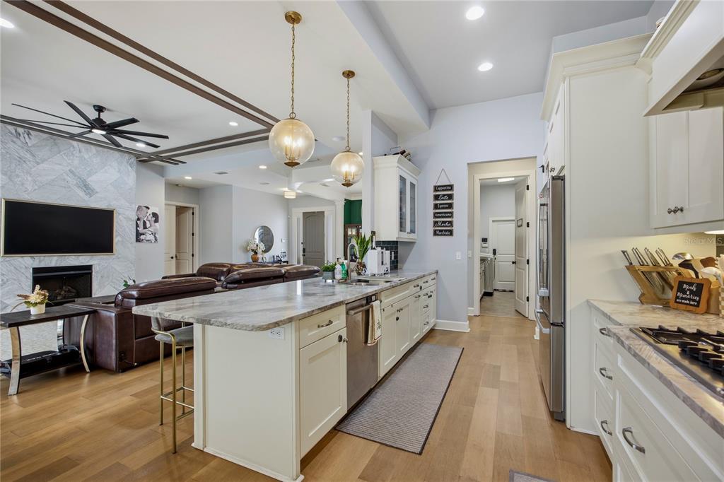 A kitchen with a large island, stone countertops, and stainless steel appliances opens to a living room — 4003 NW 63RD WAY, GAINESVILLE, FL
