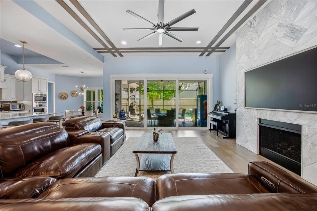 A living room features a marble fireplace, leather sofas, and a large ceiling fan — 4003 NW 63RD WAY, GAINESVILLE, FL
