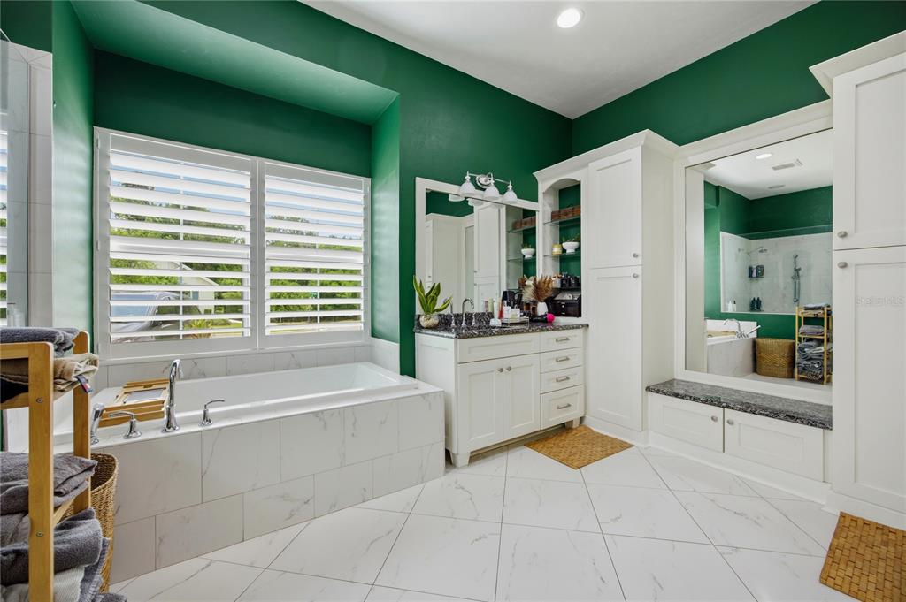 A bathroom features a soaking tub, white vanity, and green walls with white tile flooring — 4003 NW 63RD WAY, GAINESVILLE, FL