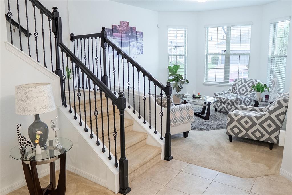 A staircase with black iron railings leads into a living room with patterned armchairs — 3231 PALATKA STREET, ORLANDO, FL