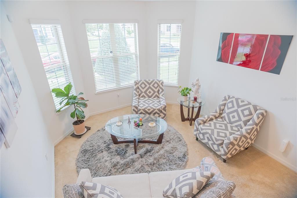 A sunroom features a circular rug, glass coffee table, and three patterned armchairs — 3231 PALATKA STREET, ORLANDO, FL