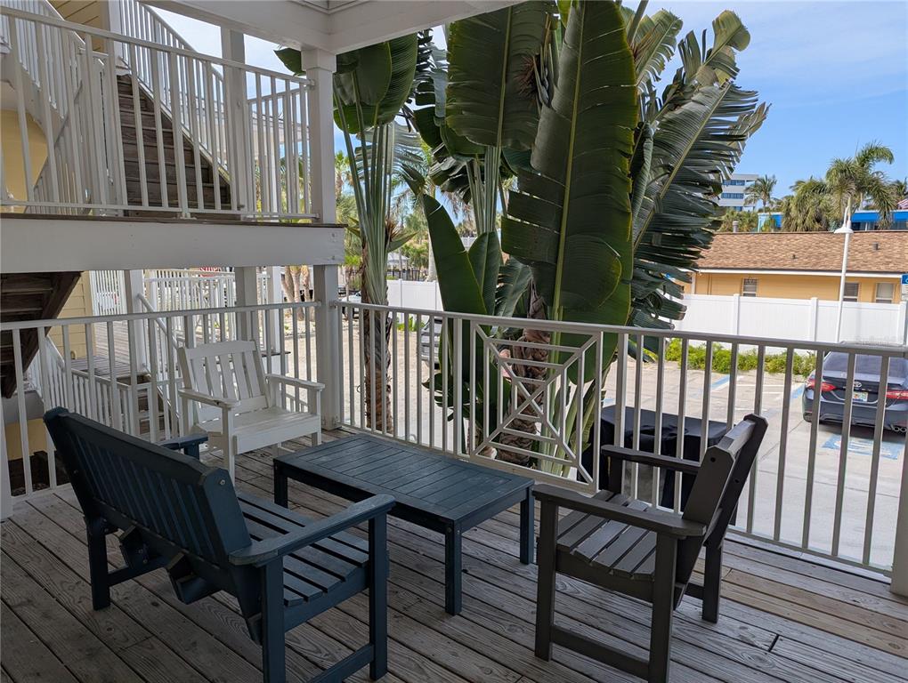 A wooden deck features outdoor furniture, a white railing, and large tropical plants — 6732 SARASEA CIRCLE UNIT 104C, SARASOTA, FL