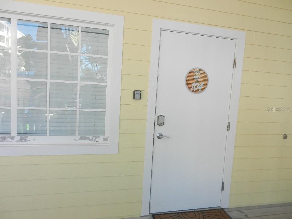 A white door with a circular sign and a window are on a yellow wall — 6732 SARASEA CIRCLE UNIT 104C, SARASOTA, FL