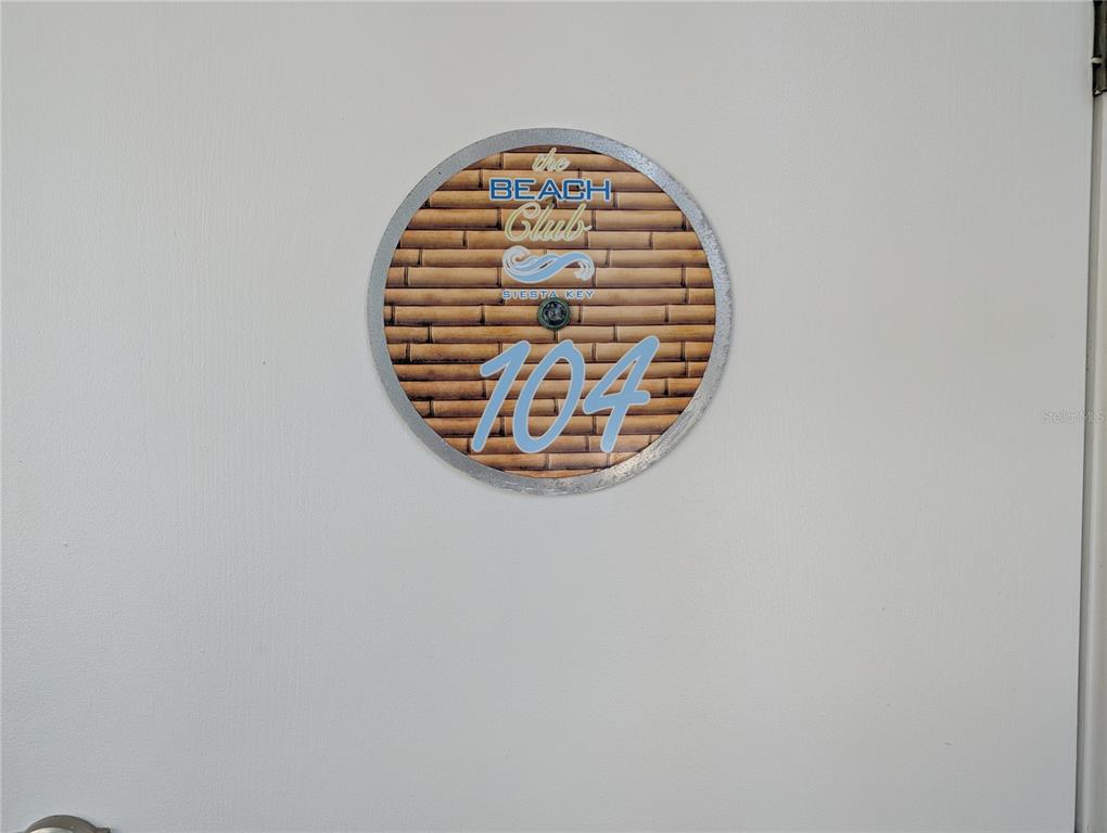 A circular sign for The Beach Club Siesta Key unit 104 is mounted on a door — 6732 SARASEA CIRCLE UNIT 104C, SARASOTA, FL