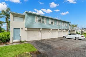 A two-story building with light blue siding, a light-colored front door, and three garage doors — 3247 38TH WAY S UNIT C, ST PETERSBURG, FL