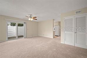 A carpeted living room features a ceiling fan, sliding glass doors, and louvered closet doors — 3247 38TH WAY S UNIT C, ST PETERSBURG, FL