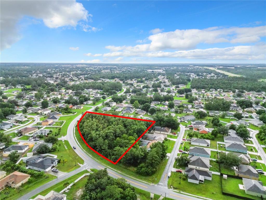 An aerial view shows a triangular, wooded vacant lot outlined in red within a neighborhood — 0 PEABODY ROAD, KISSIMMEE, FL
