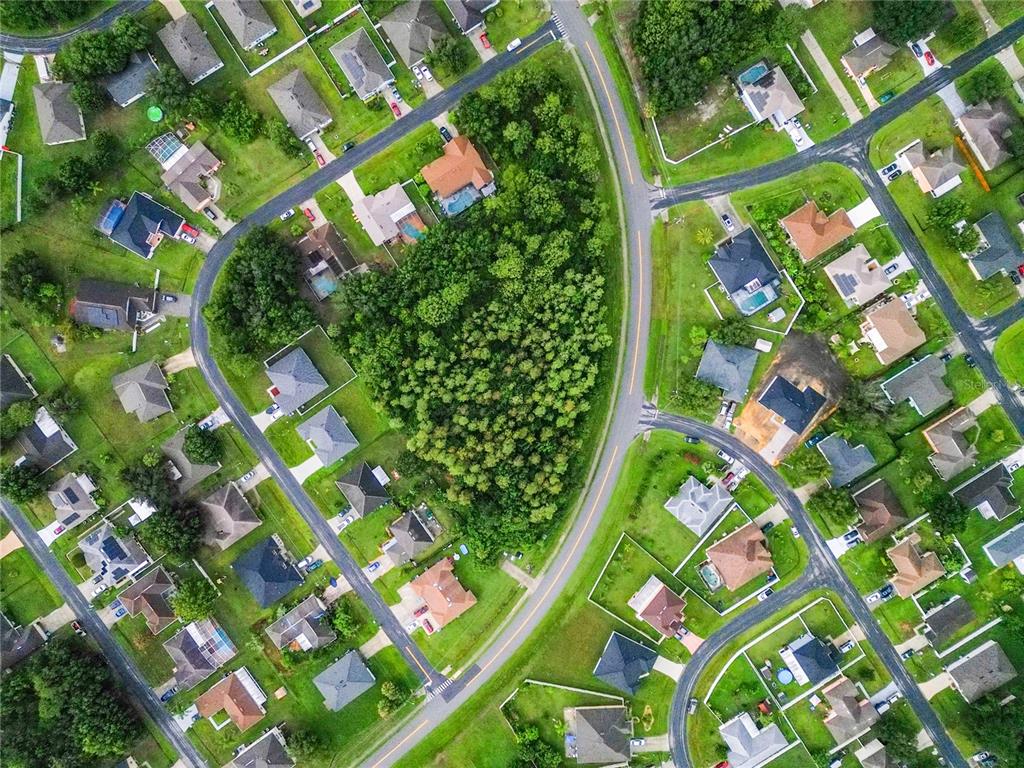 This aerial view shows a suburban neighborhood with houses surrounding a central wooded area — 0 PEABODY ROAD, KISSIMMEE, FL