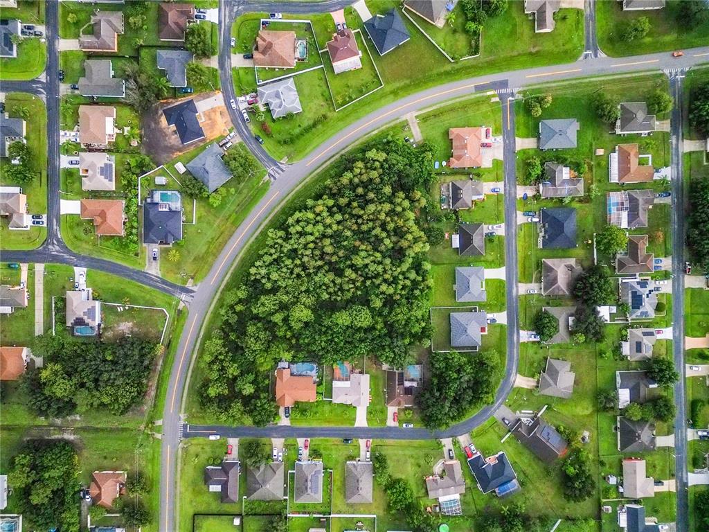 This aerial view shows a residential neighborhood with a large central wooded area — 0 PEABODY ROAD, KISSIMMEE, FL