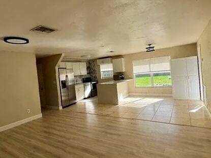 An open-concept kitchen features stainless steel appliances, white cabinetry, and a tile floor — 2831 NE Savannah Road, Jensen Beach FL 34957, JENSEN BEACH, FL