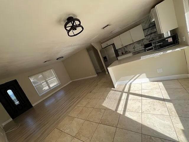 An open-concept living area features tile flooring, a kitchen with white cabinets, and a chandelier — 2831 NE Savannah Road, Jensen Beach FL 34957, JENSEN BEACH, FL