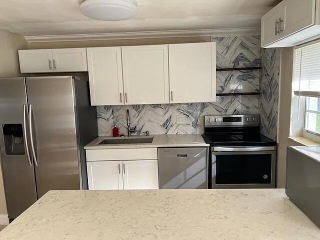 A kitchen features white cabinets, stainless steel appliances, and a herringbone-patterned marble tile backsplash — 2831 NE Savannah Road, Jensen Beach FL 34957, JENSEN BEACH, FL