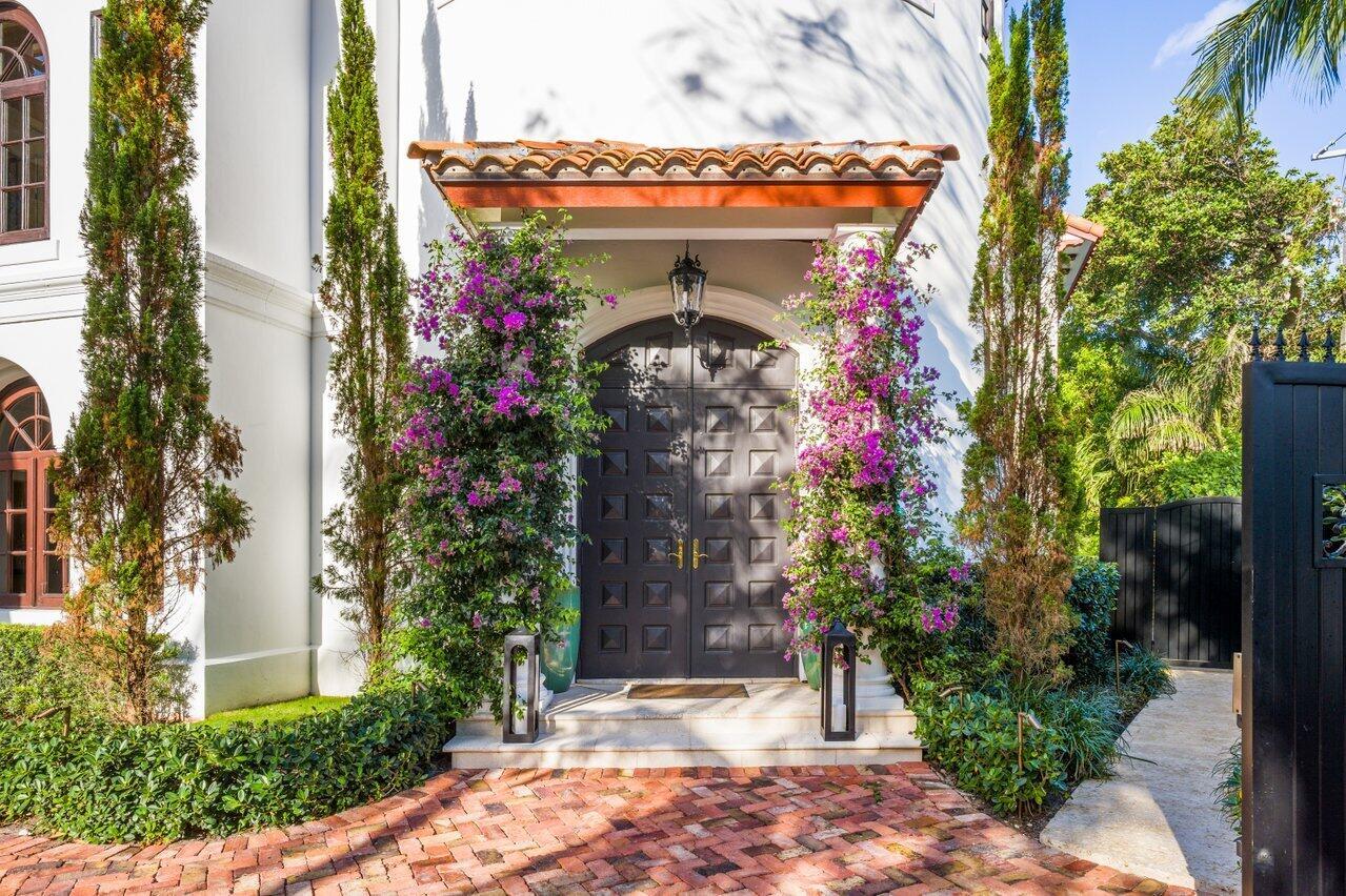 A white house entrance features a dark paneled double door framed by blooming bougainvillea — 350 E Ocean Avenue, Lantana FL 33462, LANTANA, FL