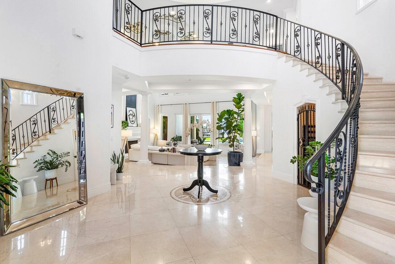 A grand foyer features a curved staircase, marble floors, and a large decorative mirror — 350 E Ocean Avenue, Lantana FL 33462, LANTANA, FL