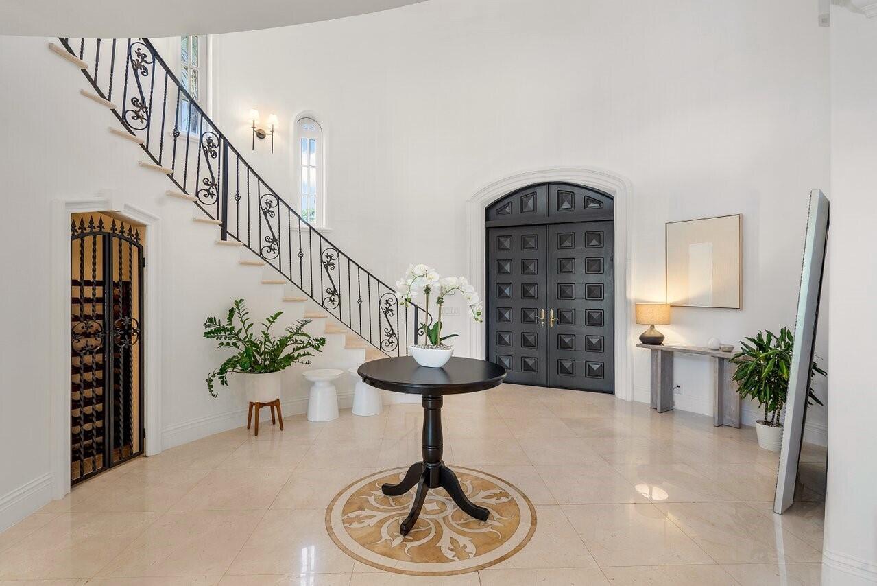 A bright foyer features a curved staircase with iron railings, marble floors, and double doors — 350 E Ocean Avenue, Lantana FL 33462, LANTANA, FL