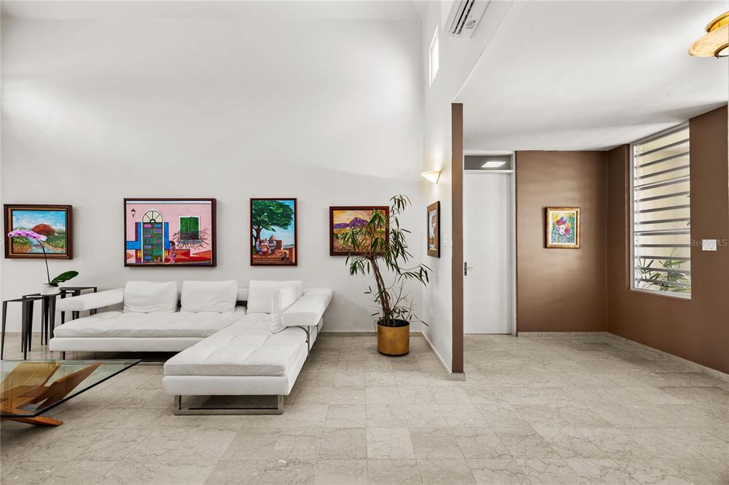 A living room features a white sectional sofa, tiled floors, and several framed paintings on walls — PASEO SAN JUAN C-8 CALLE ROGATIVA, SAN JUAN, PR