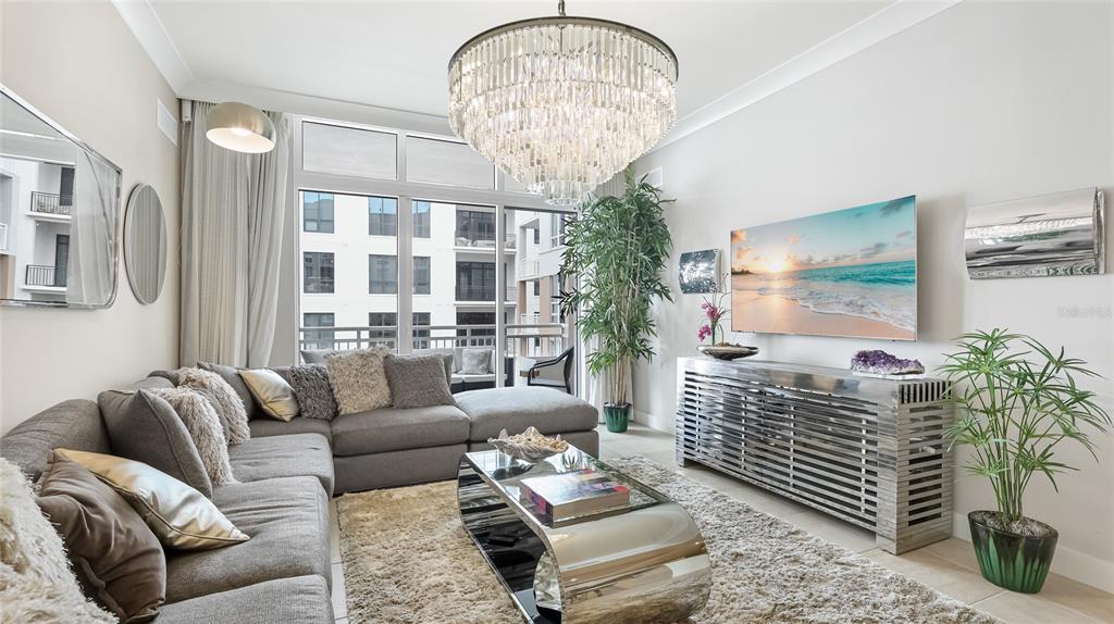 A living room features a gray sectional sofa, a crystal chandelier, and a metallic console — 1350 MAIN STREET UNIT 1503, SARASOTA, FL