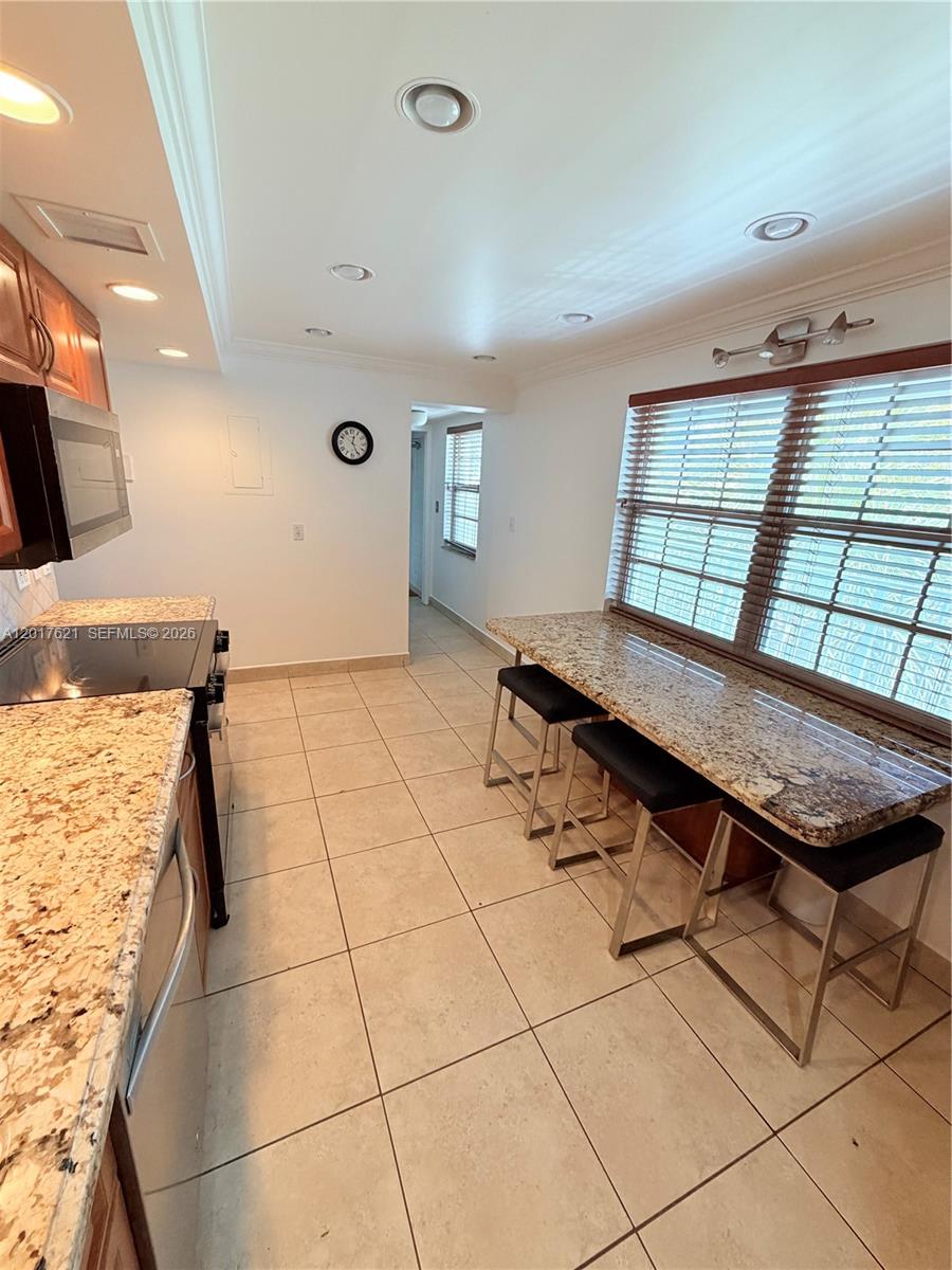 A kitchen features granite countertops, tile flooring, recessed lighting, and a breakfast bar with stools — 4020 W Palm Aire Dr # 403, Pompano Beach FL 33069, POMPANO BEACH, FL
