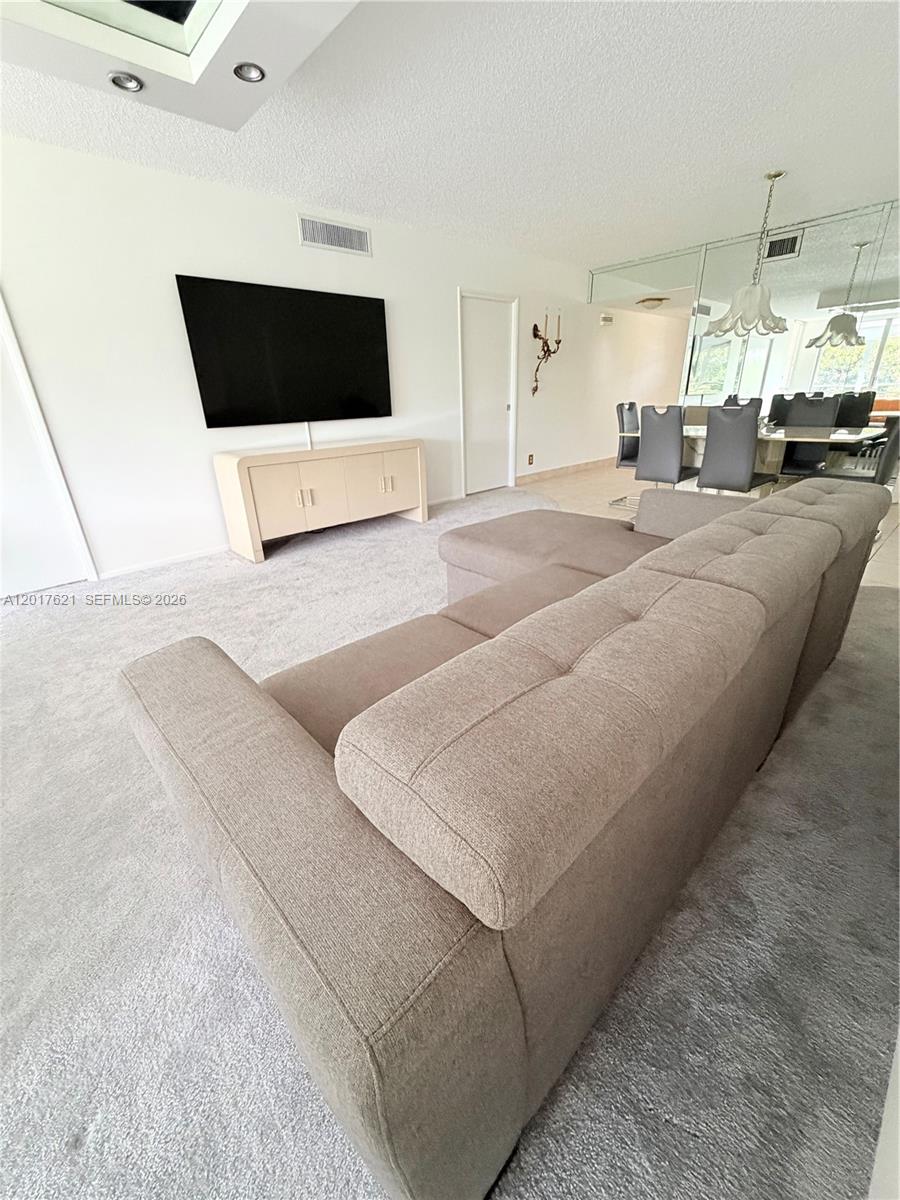 A living room features a large sectional sofa, a wall-mounted television, and a dining area — 4020 W Palm Aire Dr # 403, Pompano Beach FL 33069, POMPANO BEACH, FL