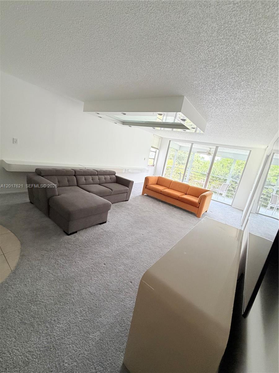 A living room features gray carpet, a gray sectional, an orange sofa, and a ceiling light — 4020 W Palm Aire Dr # 403, Pompano Beach FL 33069, POMPANO BEACH, FL