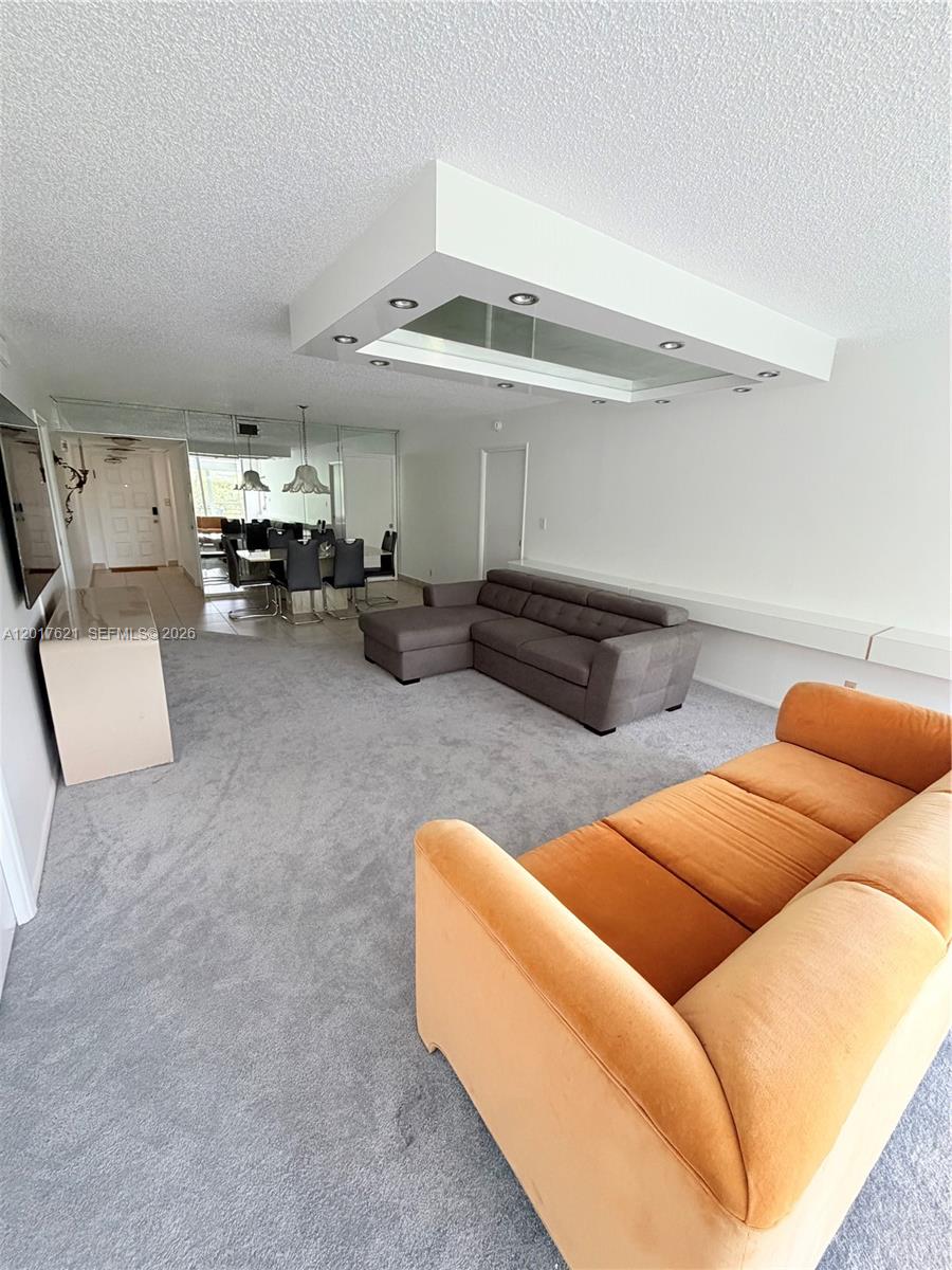 A living room features gray carpeting, a gray sectional, an orange sofa, and a ceiling light — 4020 W Palm Aire Dr # 403, Pompano Beach FL 33069, POMPANO BEACH, FL