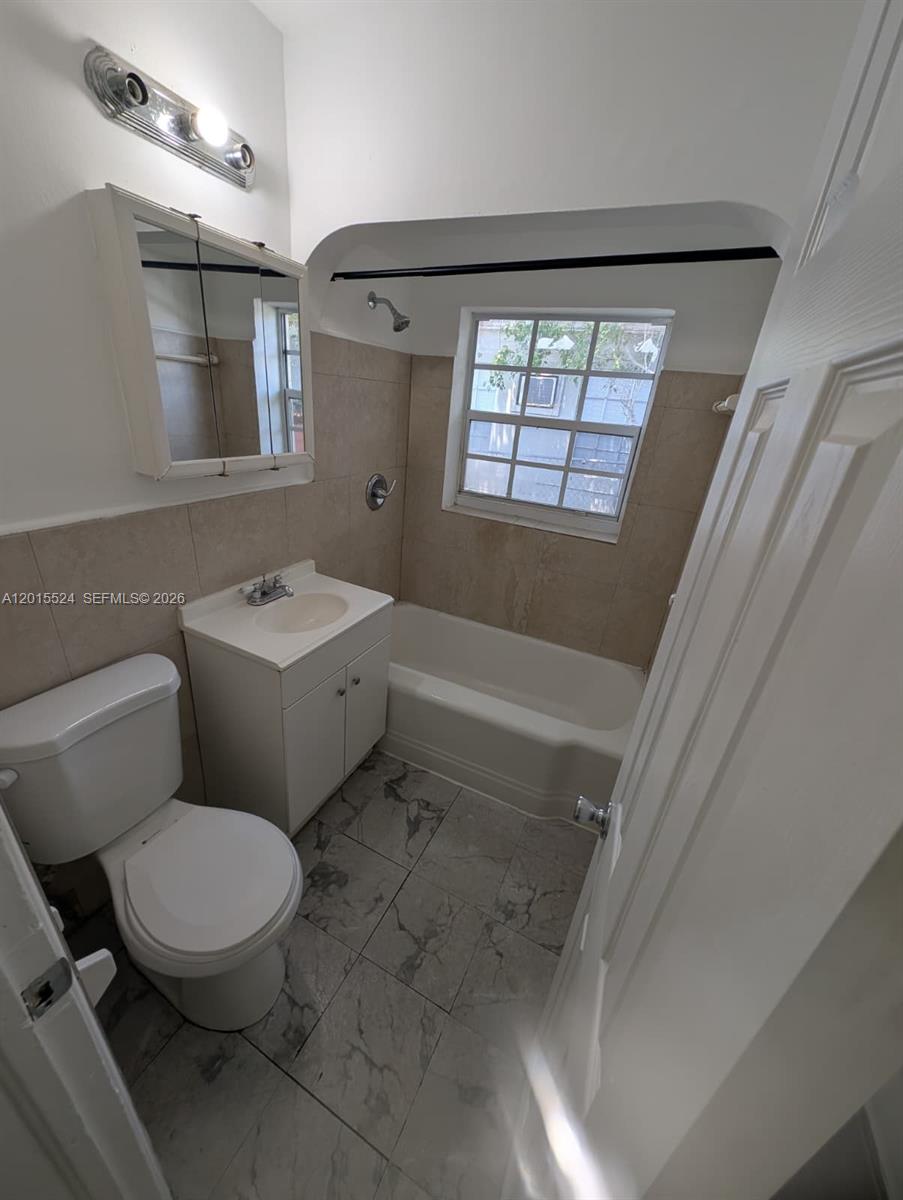 A small bathroom features a white vanity, a toilet, and a tiled shower-tub combination — 2316 Madison St # 19, Hollywood FL 33020, HOLLYWOOD, FL