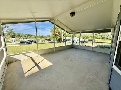 A screened-in porch with a concrete floor overlooks a grassy yard and trees — 470 HILLTOP COURT, DELAND, FL