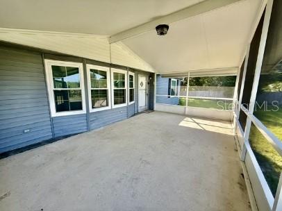 A covered, screened-in porch with gray siding, multiple windows, and a concrete floor — 470 HILLTOP COURT, DELAND, FL