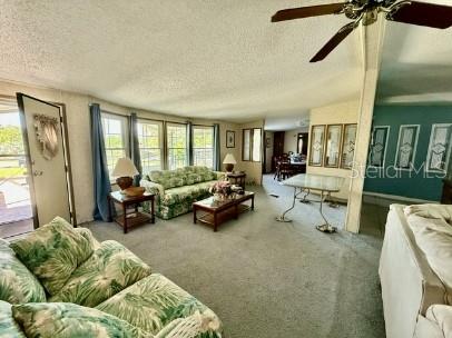 A living room features a floral sofa, a ceiling fan, and a dining area beyond — 470 HILLTOP COURT, DELAND, FL