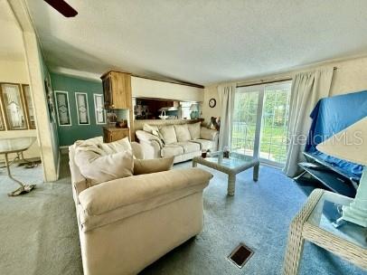 A living room features a beige sofa, a coffee table, and sliding glass doors — 470 HILLTOP COURT, DELAND, FL