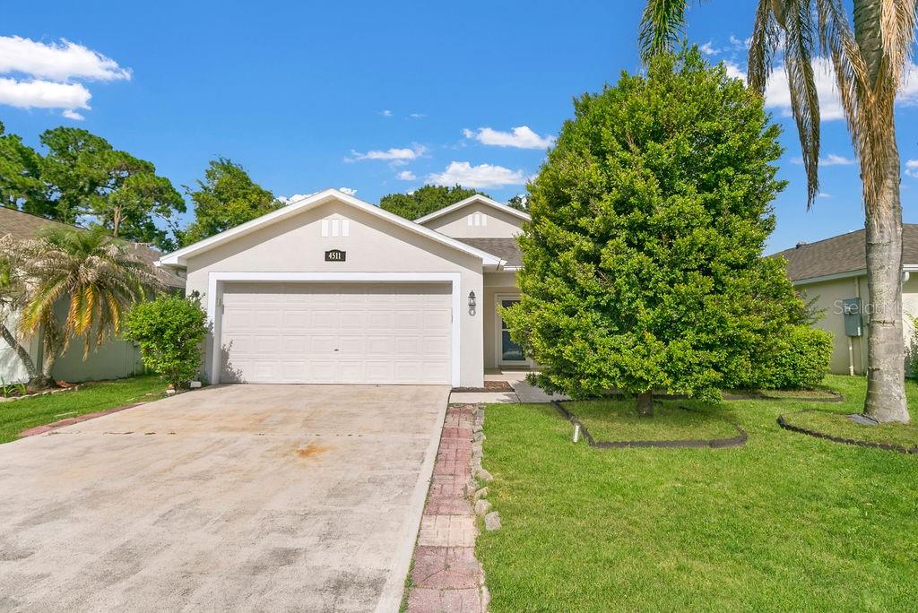 A single-story house with a beige exterior, a two-car garage, and a front lawn — 4511 DERBYSHIRE DRIVE, TITUSVILLE, FL