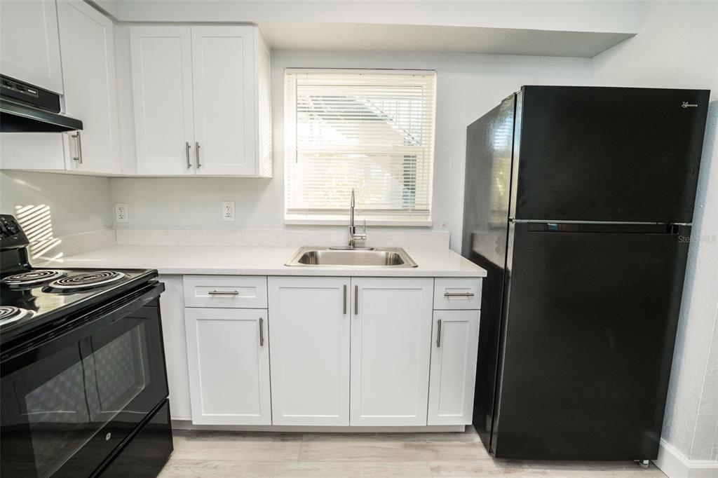 A kitchen features white cabinets, a stainless steel sink, and black appliances against light walls — 11312 N 52ND STREET UNIT A11, TAMPA, FL