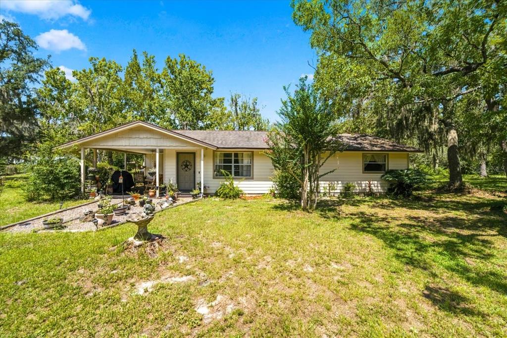 A single-story house with light siding sits behind a large tree with a hanging swing — 15535 RENEE LANE, HUDSON, FL