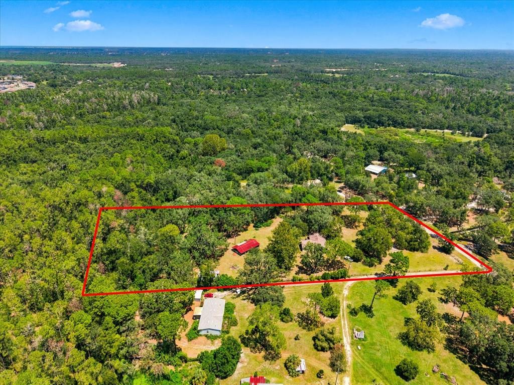 An aerial view shows a wooded property with two buildings outlined in red — 15535 RENEE LANE, HUDSON, FL