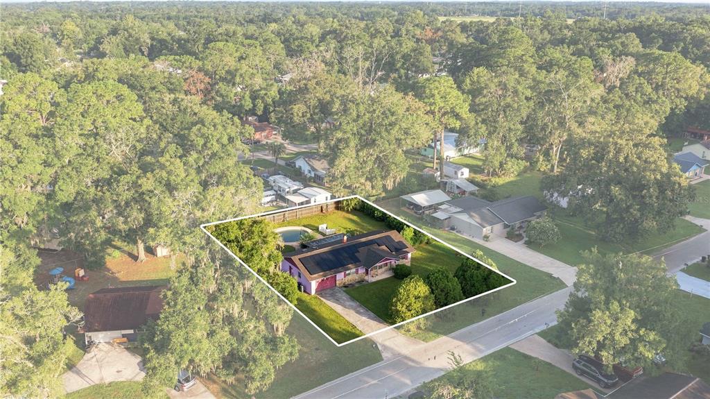 An aerial view shows a single-story house with solar panels and a backyard swimming pool — 4950 NE 23RD AVENUE, OCALA, FL
