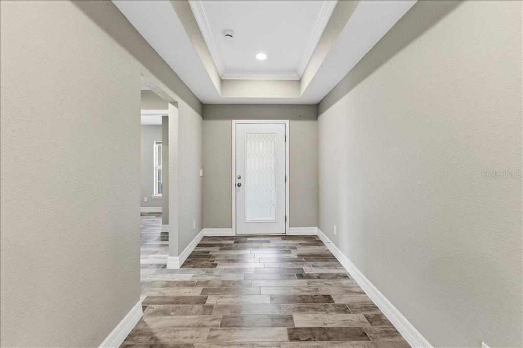 A foyer with a tray ceiling, light gray walls, and wood-look tile flooring — 138 SUNNY WAY, ROTONDA WEST, FL