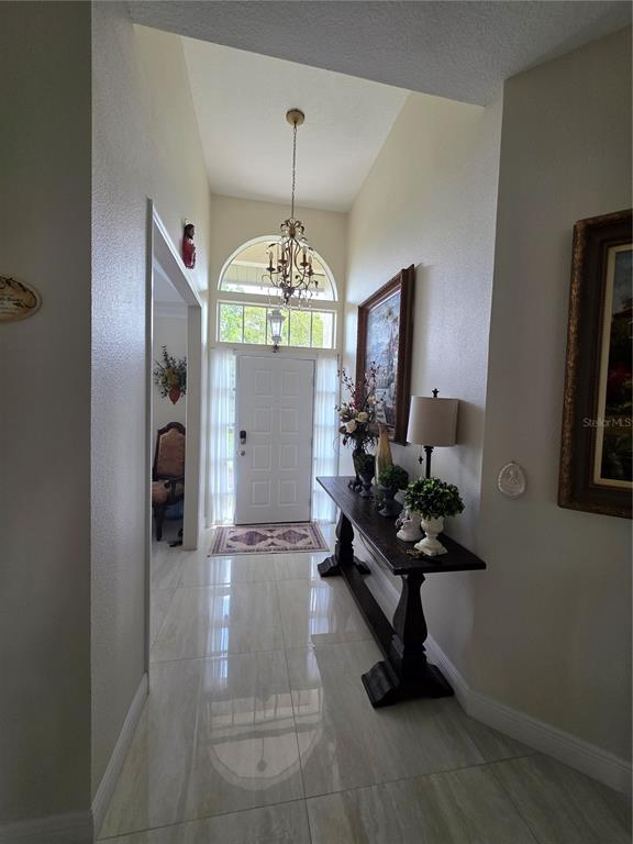 A bright entryway features a high ceiling, a chandelier, tile flooring, and a console table — 802 KAYWOOD DRIVE UNIT 802, ORLANDO, FL