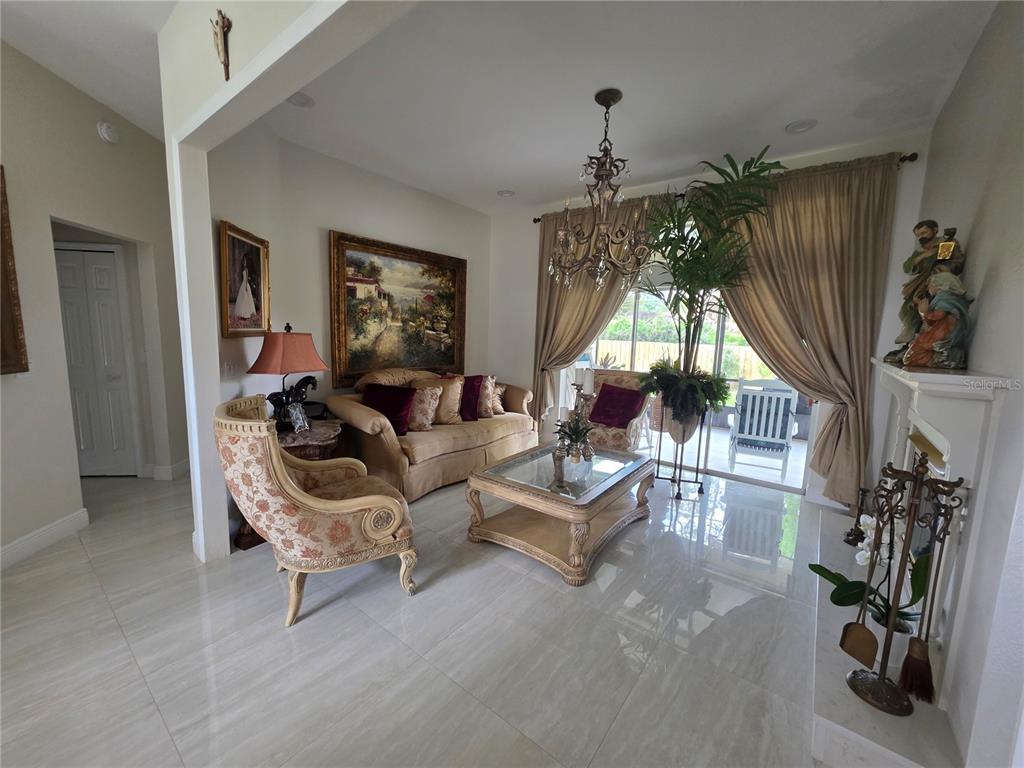 A living room features tile floors, a chandelier, a sofa, and a large window — 802 KAYWOOD DRIVE UNIT 802, ORLANDO, FL