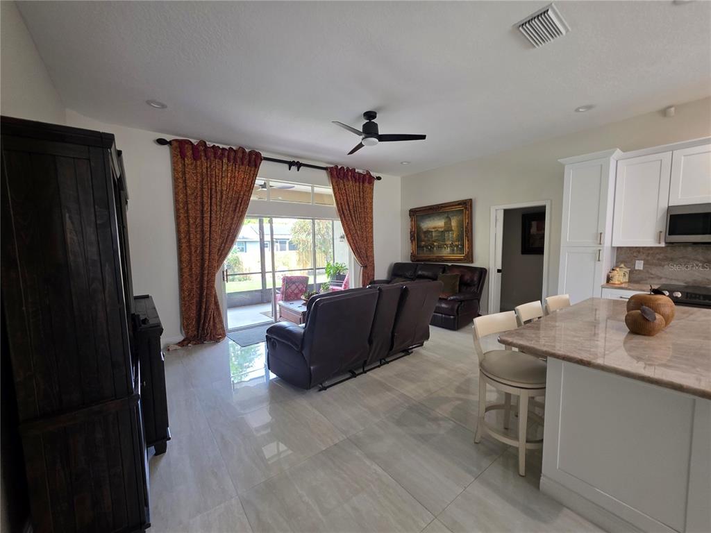 An open-concept living room features tile flooring, a kitchen island, and sliding glass patio doors — 802 KAYWOOD DRIVE UNIT 802, ORLANDO, FL