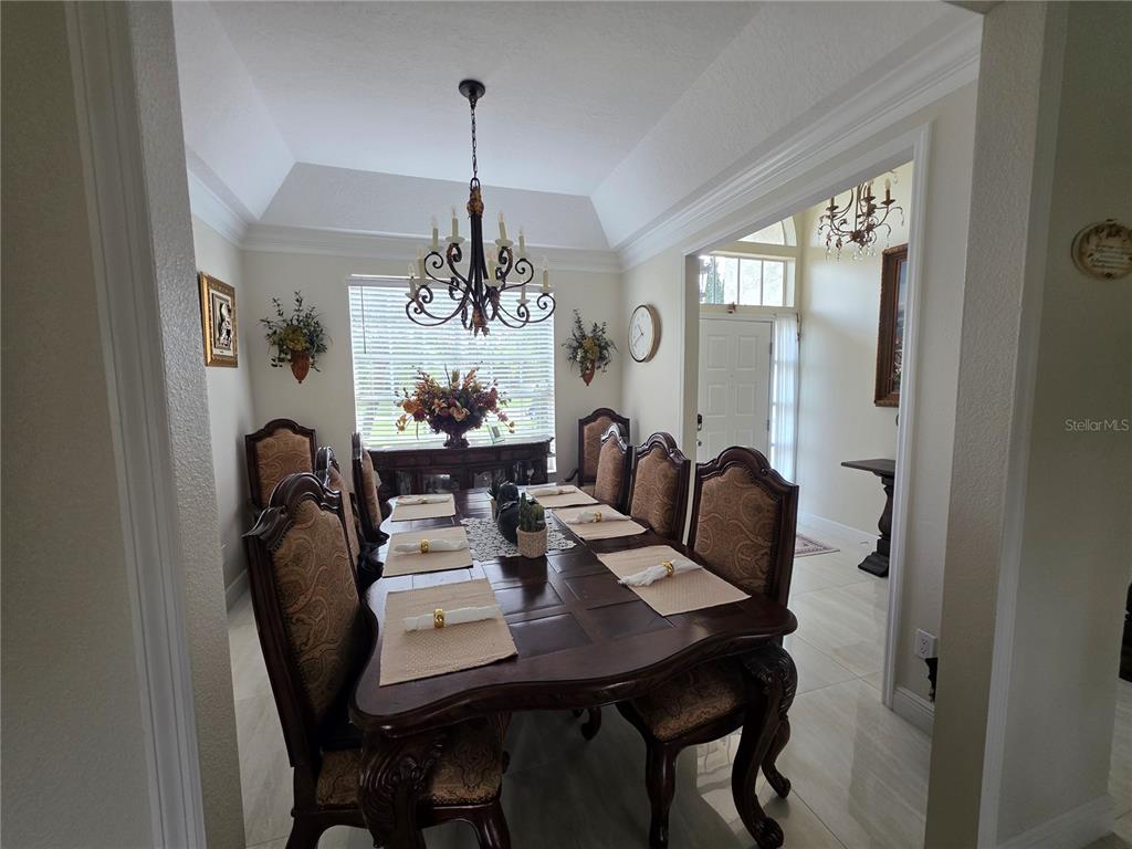 A formal dining room features a dark wood table, upholstered chairs, and a tray ceiling — 802 KAYWOOD DRIVE UNIT 802, ORLANDO, FL
