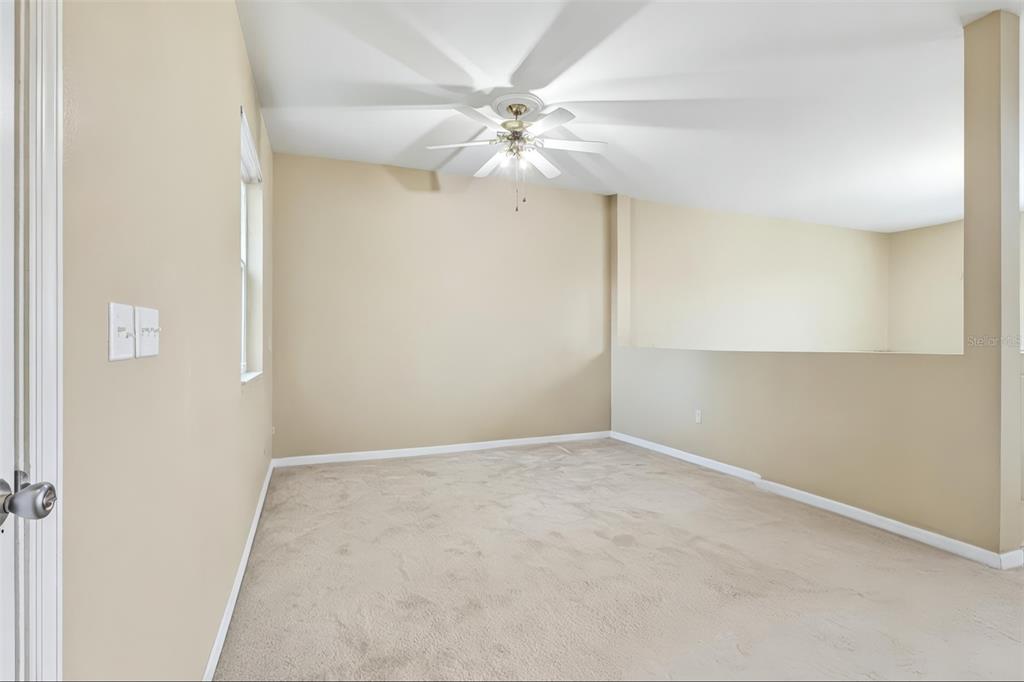 An empty room with beige walls, carpeted flooring, and a ceiling fan — 1585 AUBURN HILLS COURT, TAVARES, FL