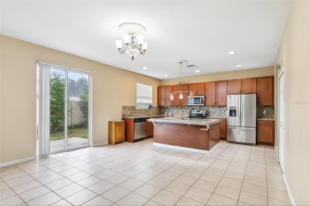 A kitchen with wood cabinets, a center island, stainless steel appliances, and tile flooring — 1585 AUBURN HILLS COURT, TAVARES, FL